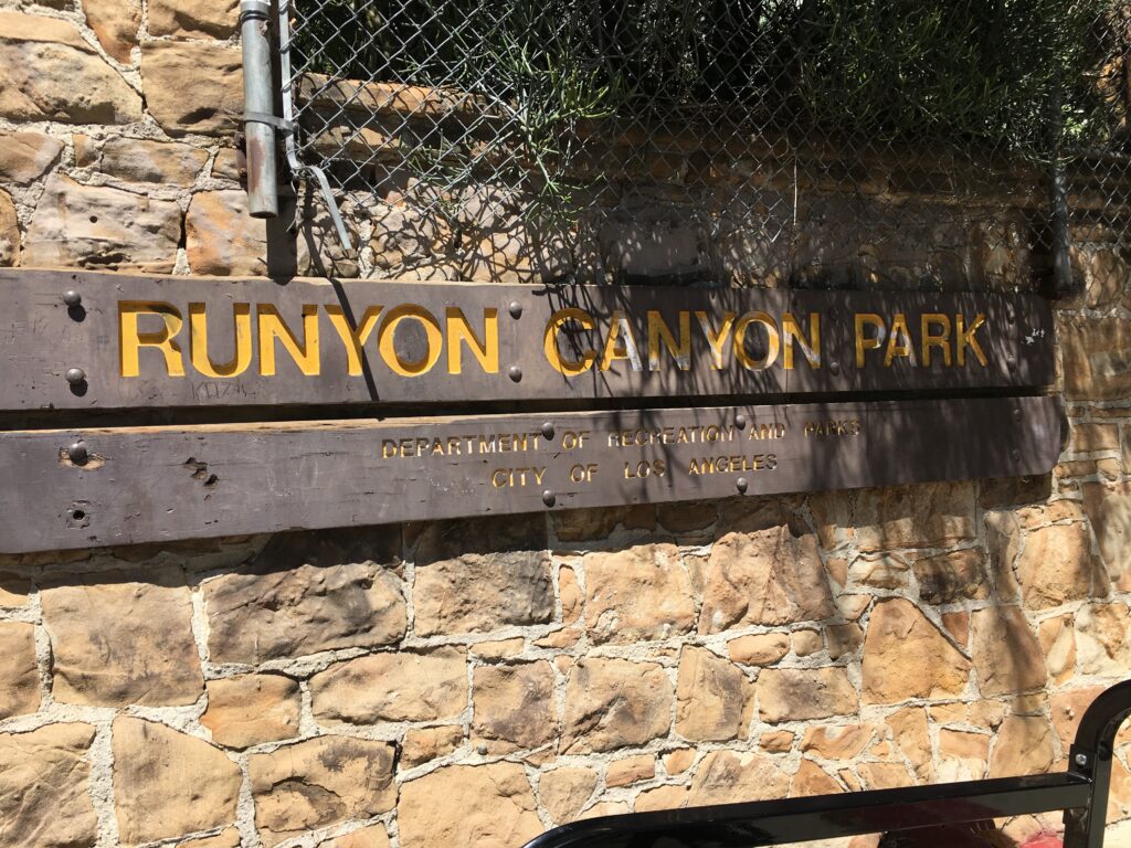 Photo of Runyon Canyon Park sign near Magic Castle Hotel and Hollywood Walk of Fame.